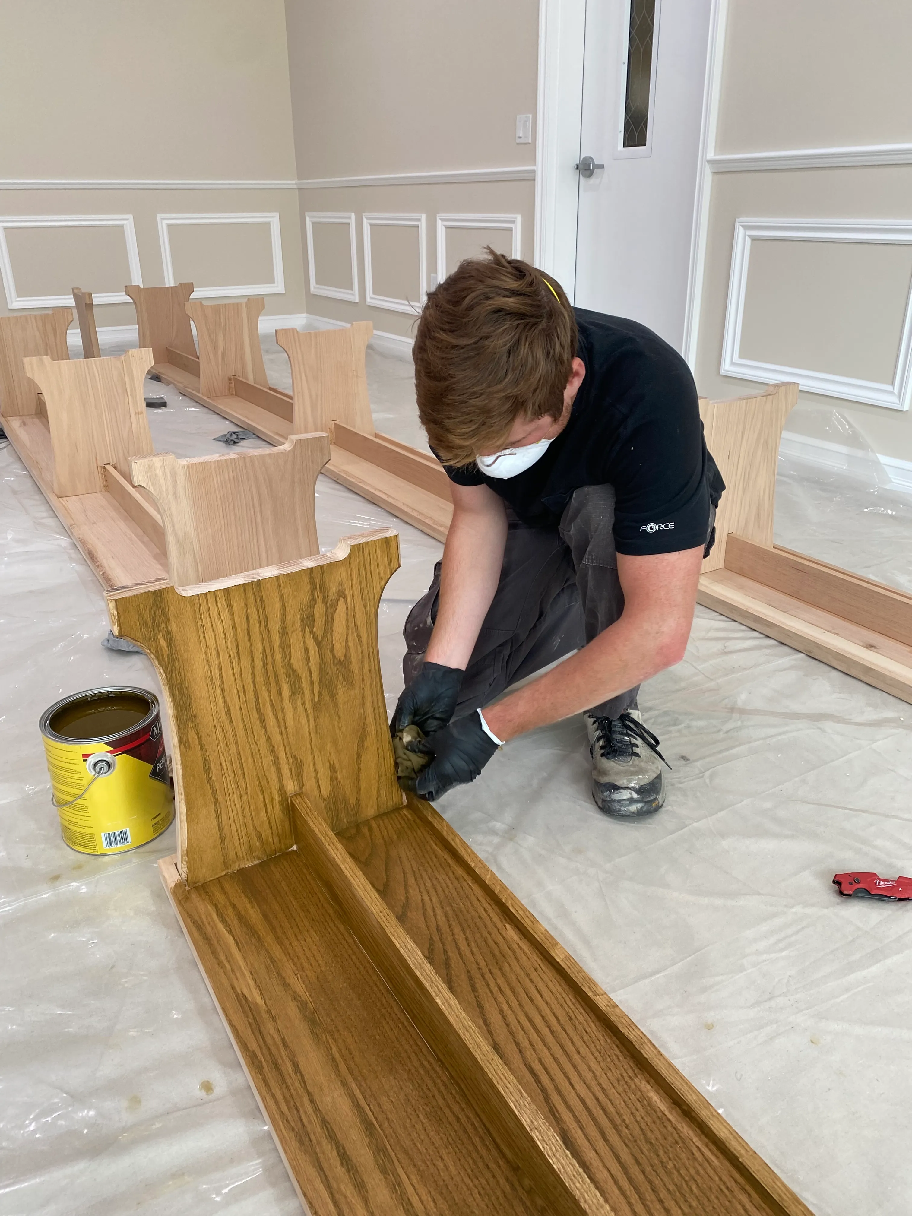 Craftsman hand-staining a custom oak bench
