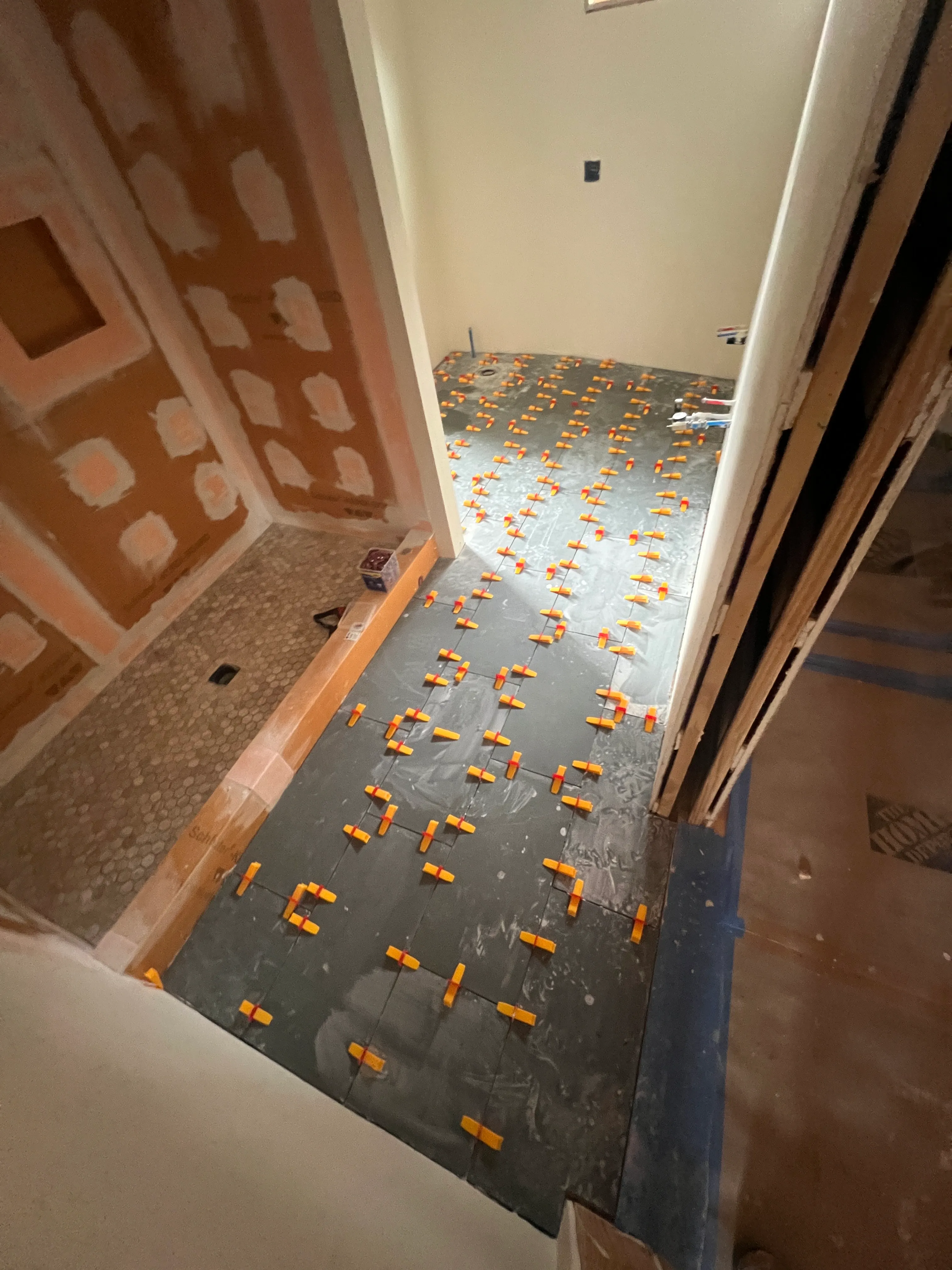 Dark slate floor tile being set with leveling clips