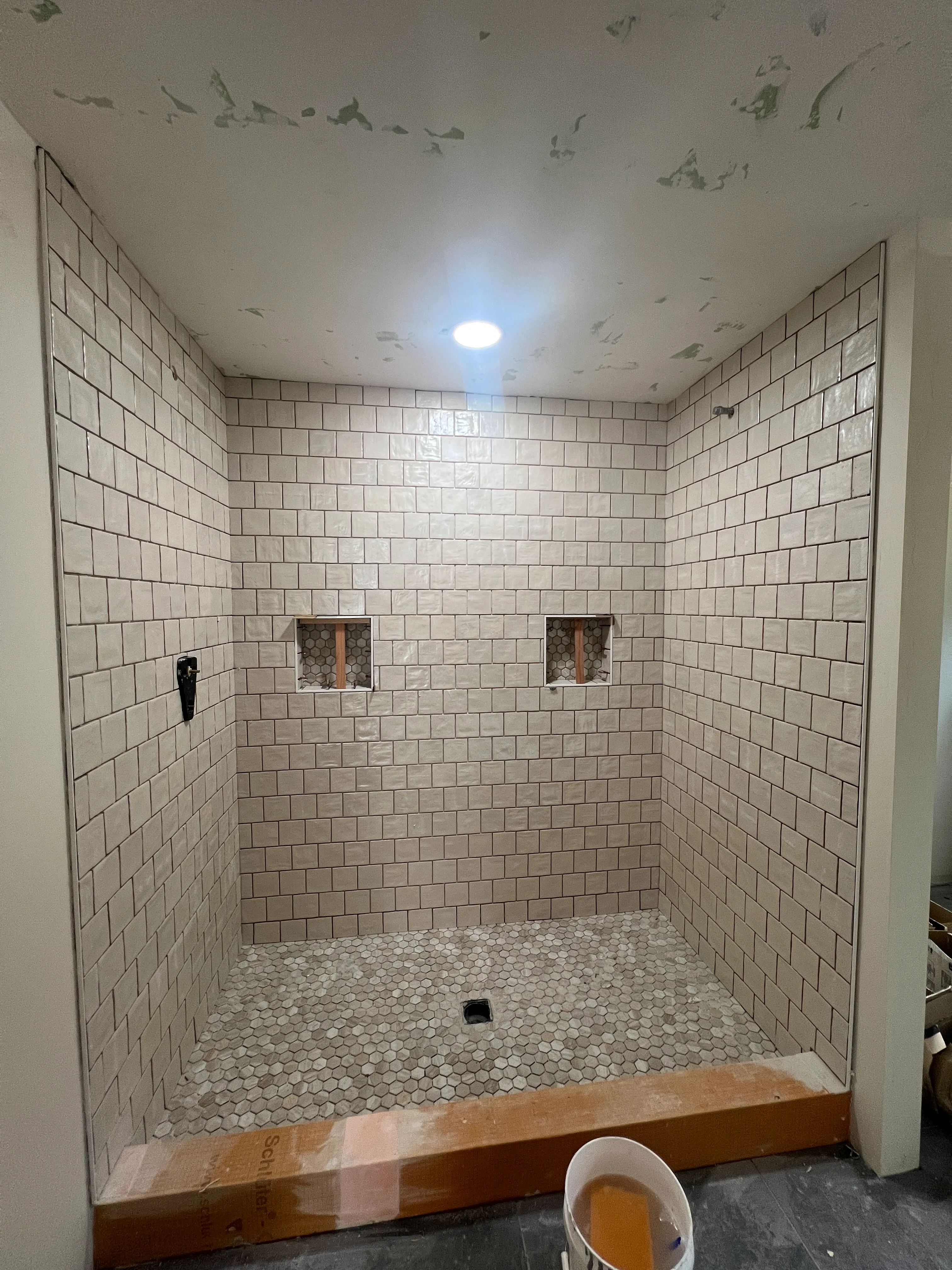 White subway tile shower with hex mosaic niches